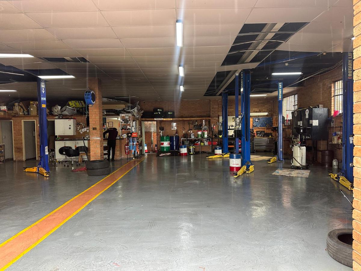 Inside the 5AB workshop: a wide, clean service floor with blue two-post hoists and the customer service counter
